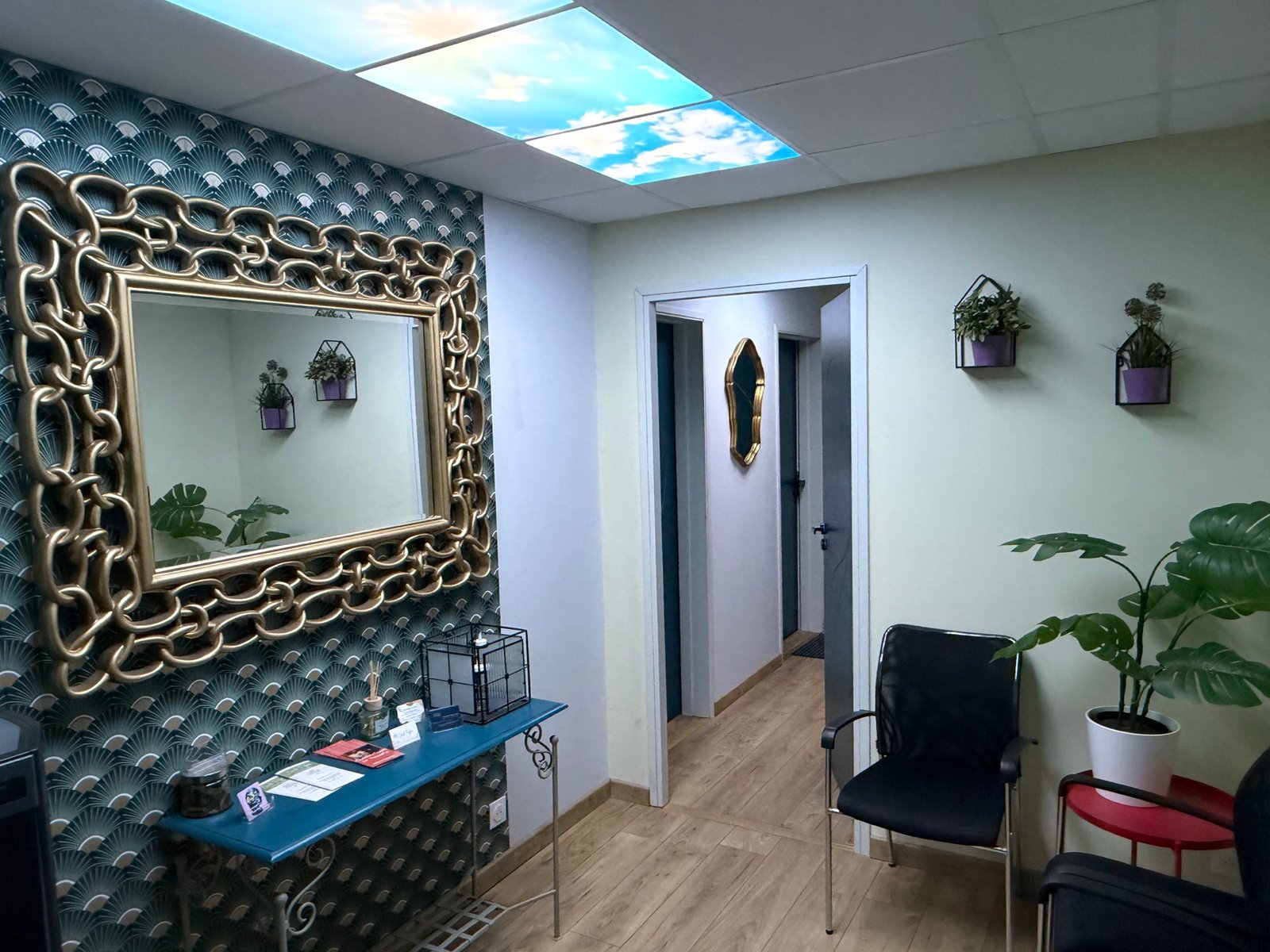 L’accueil et la salle d’attente partagée, avec sièges, plantes et console bleue.
